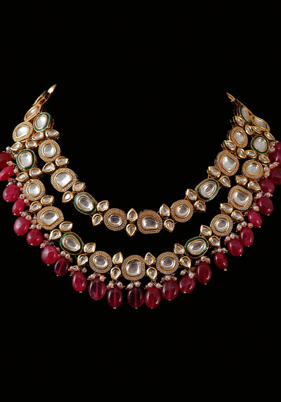 Gold Toned 2 Layered American Diamond Studded Kundan Neklace with Ruby Colored Droplets and a Pair of Earrings